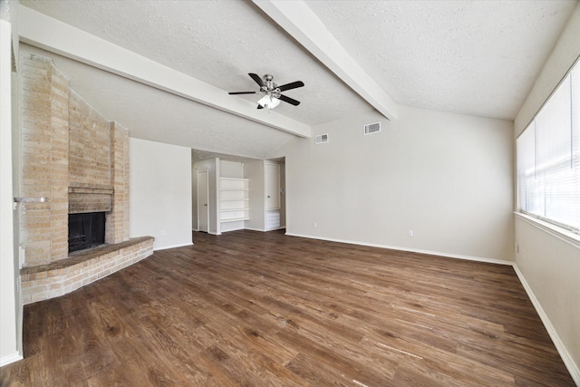 unfurnished living room with visible vents, lofted ceiling with beams, wood finished floors, a textured ceiling, and a fireplace