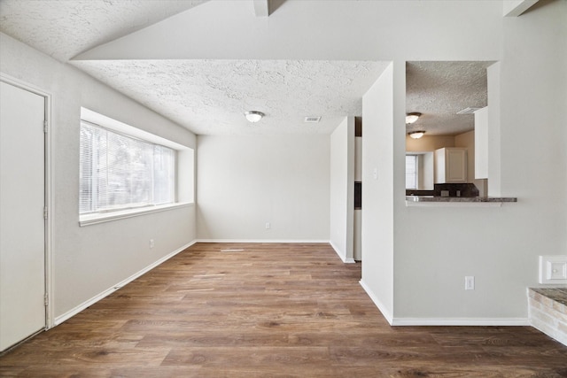 spare room with a textured ceiling, baseboards, and wood finished floors