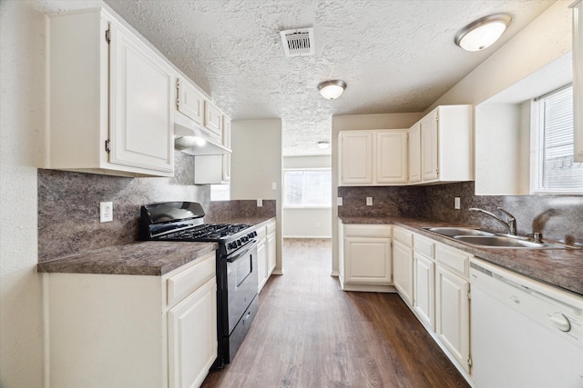 kitchen featuring dark wood-style floors, stainless steel range with gas stovetop, white dishwasher, a sink, and under cabinet range hood