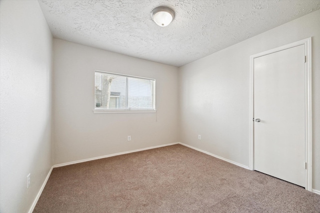 carpeted spare room featuring baseboards and a textured ceiling