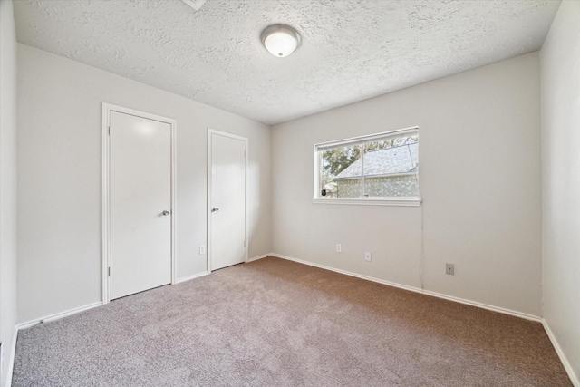 unfurnished bedroom with a textured ceiling, carpet, and baseboards