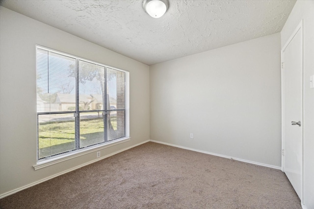 unfurnished room with carpet, baseboards, and a textured ceiling