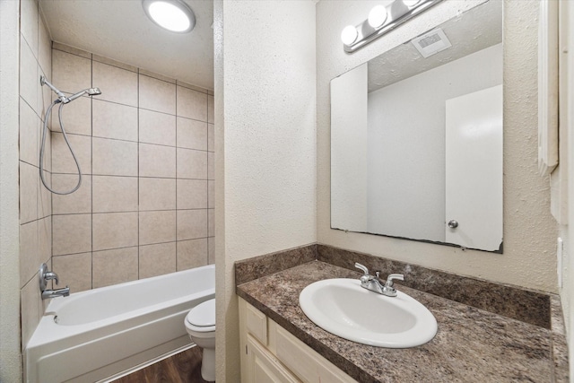 full bath with bathing tub / shower combination, a textured wall, toilet, vanity, and wood finished floors