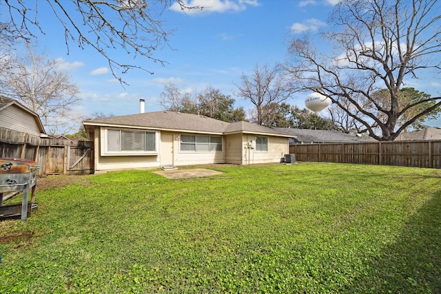 rear view of property with a fenced backyard, cooling unit, and a lawn