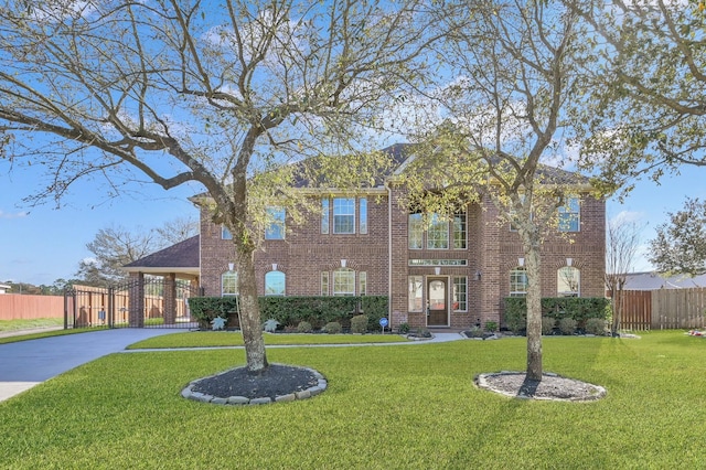 view of front of property with a front yard, fence, brick siding, and driveway