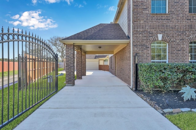 view of patio featuring concrete driveway, fence, and a garage