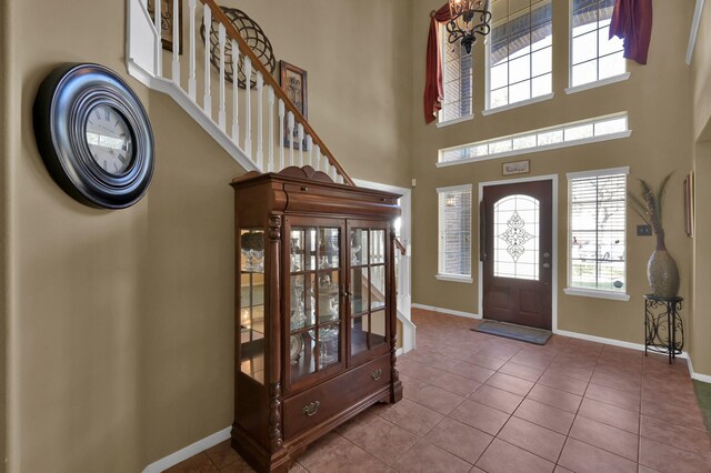 entrance foyer with tile patterned floors, baseboards, and a towering ceiling