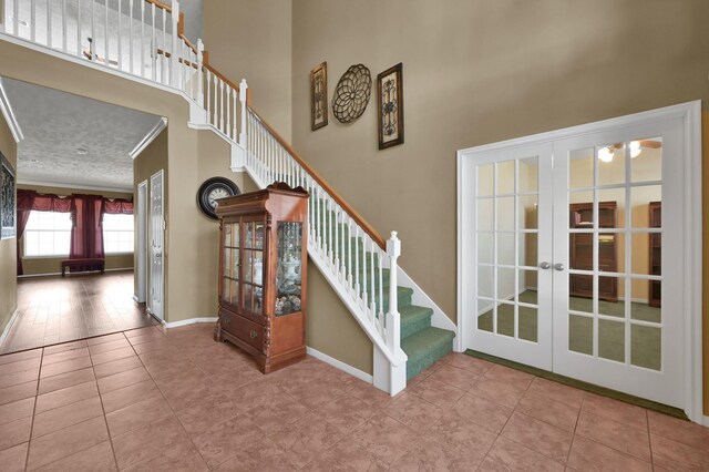 stairs featuring a textured ceiling, french doors, baseboards, and a towering ceiling