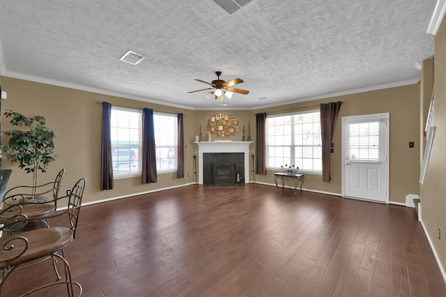 unfurnished living room featuring visible vents, crown molding, a fireplace with flush hearth, dark wood-style floors, and a ceiling fan