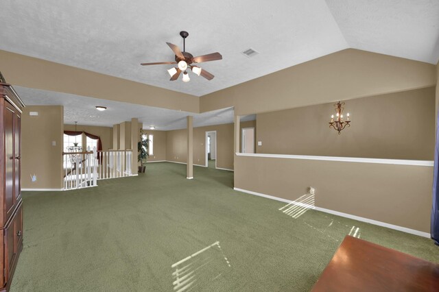 carpeted empty room featuring visible vents, baseboards, vaulted ceiling, ceiling fan with notable chandelier, and a textured ceiling