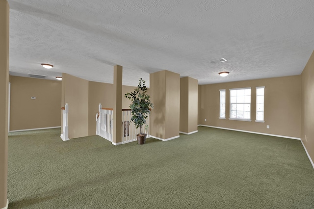 carpeted spare room with visible vents, baseboards, and a textured ceiling