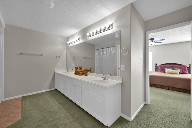 ensuite bathroom with a sink, baseboards, a textured ceiling, and carpet flooring