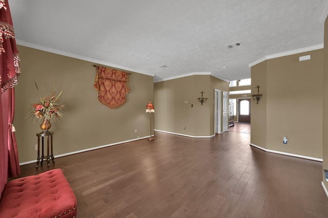 unfurnished living room featuring visible vents, crown molding, baseboards, and wood finished floors