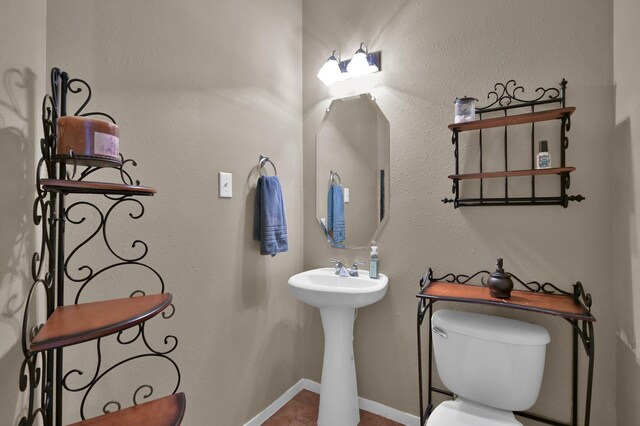 half bathroom with tile patterned floors, baseboards, and toilet