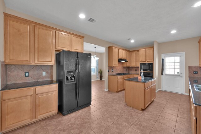 kitchen with dark countertops, visible vents, light brown cabinets, a kitchen island, and black appliances