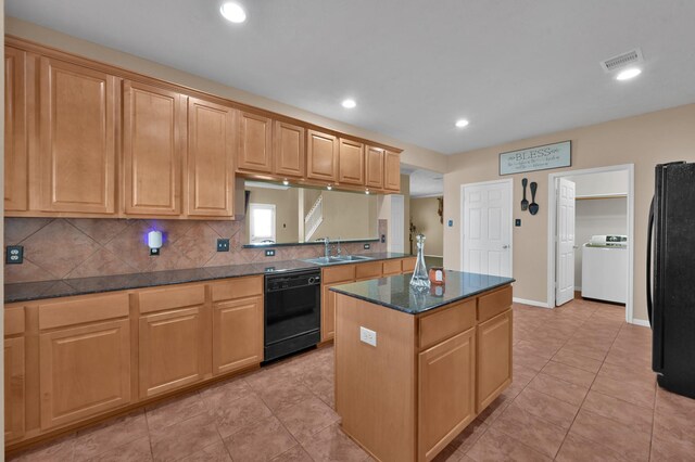 kitchen with black appliances, a sink, a center island, decorative backsplash, and washer / dryer