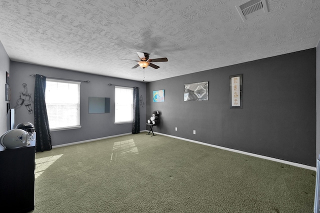 carpeted spare room with visible vents, ceiling fan, a textured ceiling, and baseboards