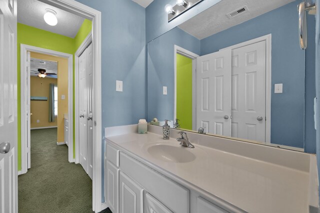 bathroom with visible vents, a textured ceiling, vanity, and baseboards