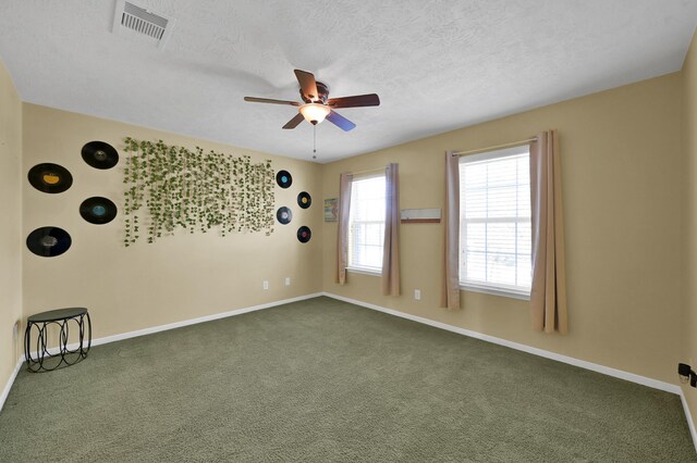 spare room featuring a ceiling fan, visible vents, dark carpet, and baseboards