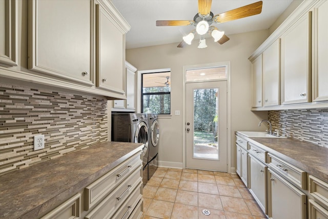 kitchen featuring dark countertops, backsplash, washer and clothes dryer, light tile patterned floors, and a sink