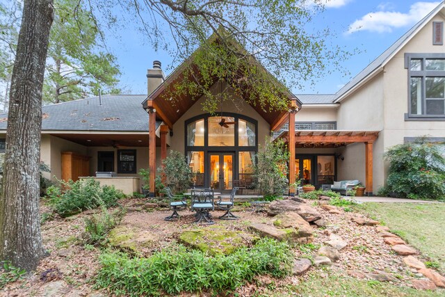 back of property with stucco siding, french doors, a chimney, and roof with shingles