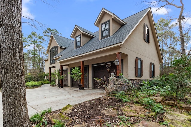 view of front facade with a porch, an attached garage, driveway, and stucco siding