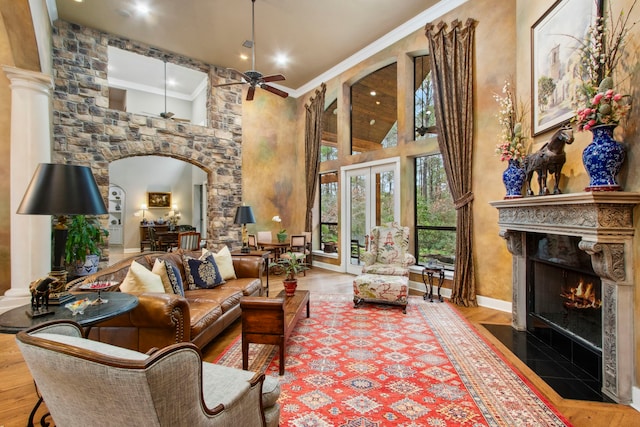 living room with ornamental molding, a ceiling fan, wood finished floors, a high end fireplace, and arched walkways