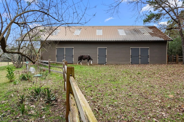 rear view of property featuring metal roof, a lawn, an outdoor structure, and fence