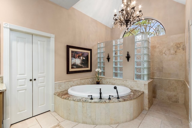 bathroom featuring tile patterned floors, a notable chandelier, lofted ceiling, and a garden tub