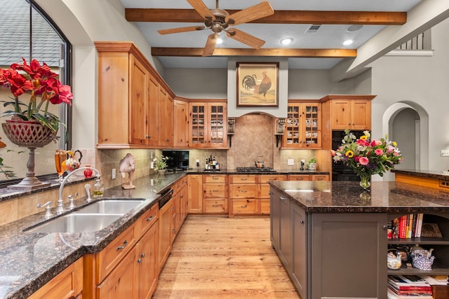 kitchen featuring beamed ceiling, tasteful backsplash, light wood finished floors, and a sink