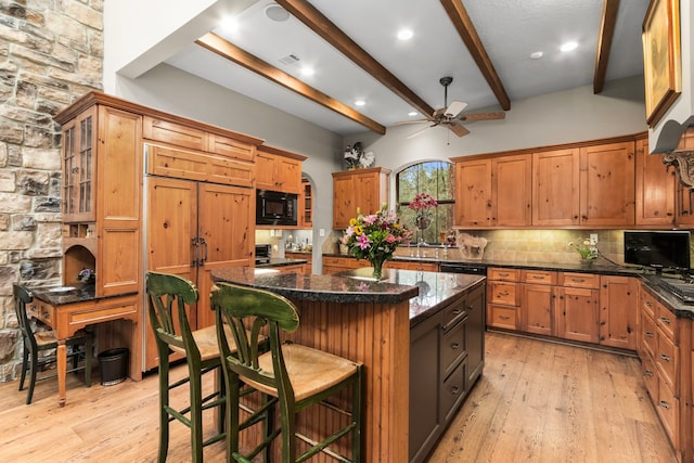 kitchen with beam ceiling, black appliances, tasteful backsplash, a kitchen island, and light wood finished floors