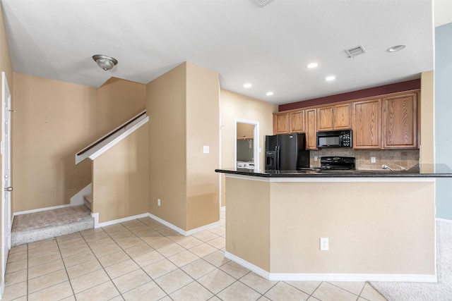 kitchen with visible vents, light tile patterned flooring, decorative backsplash, black appliances, and dark countertops