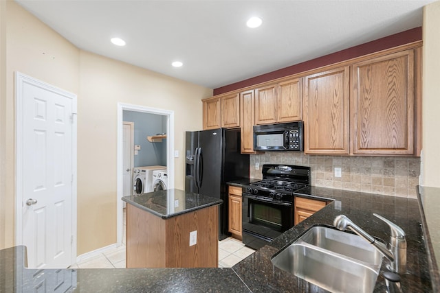 kitchen with black appliances, a sink, tasteful backsplash, light tile patterned floors, and washing machine and clothes dryer