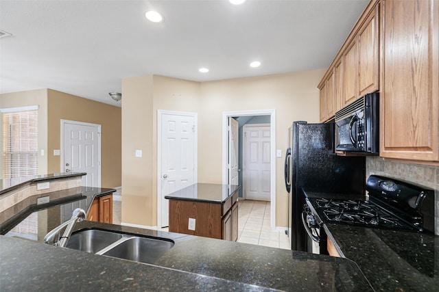 kitchen with light tile patterned floors, a kitchen island, a sink, gas range oven, and black microwave