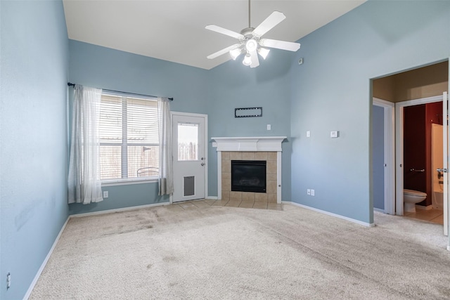 unfurnished living room with high vaulted ceiling, carpet, baseboards, and a tile fireplace