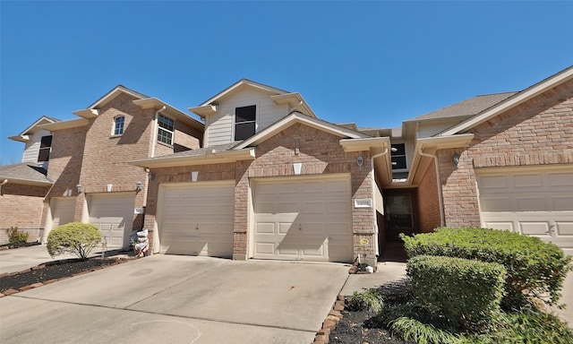 townhome / multi-family property featuring brick siding, driveway, and a garage