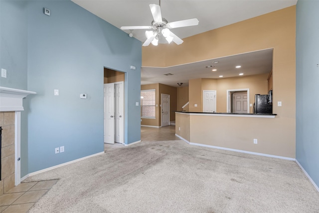 unfurnished living room with light carpet, a ceiling fan, recessed lighting, baseboards, and a tile fireplace