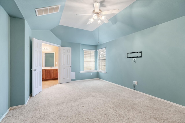 unfurnished bedroom with baseboards, visible vents, lofted ceiling, ensuite bathroom, and light carpet