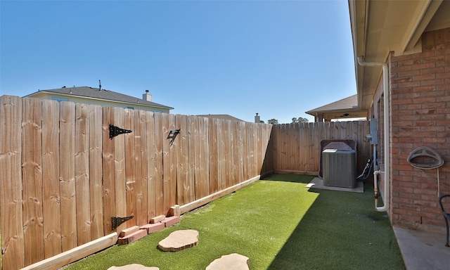 view of yard with a fenced backyard and central AC