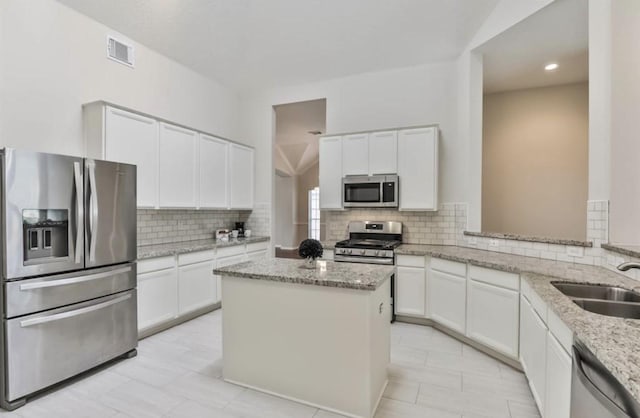 kitchen with stainless steel appliances, visible vents, backsplash, white cabinetry, and a sink