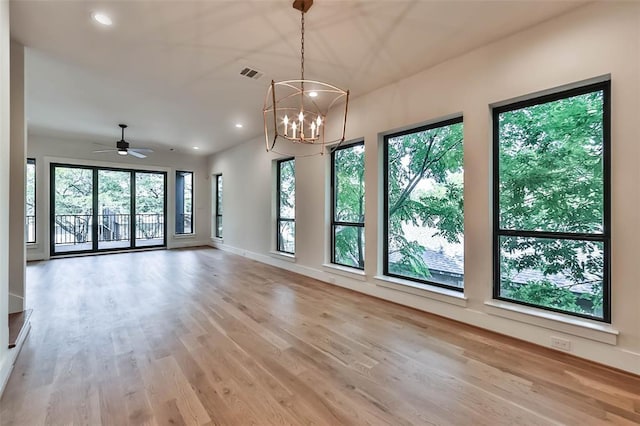 empty room featuring recessed lighting, visible vents, wood finished floors, baseboards, and ceiling fan with notable chandelier