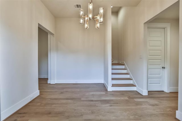 staircase featuring a notable chandelier, baseboards, visible vents, and wood finished floors