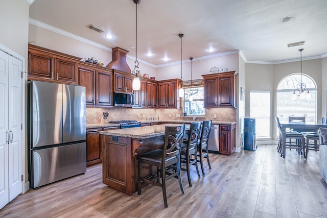 kitchen featuring visible vents, a kitchen island, backsplash, stainless steel appliances, and light wood-style floors