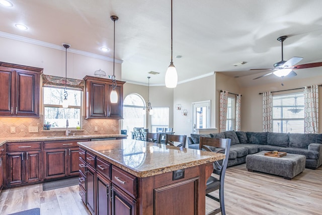 kitchen with a sink, light wood-style flooring, tasteful backsplash, and a breakfast bar area