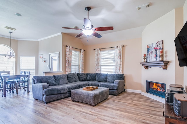 living area with light wood finished floors, visible vents, crown molding, and a glass covered fireplace