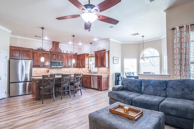 living area with visible vents, light wood-style flooring, a ceiling fan, and ornamental molding