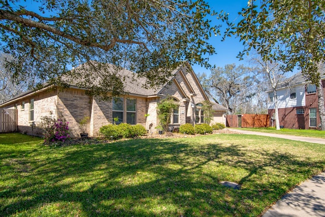 view of front of house with brick siding, a front lawn, and fence