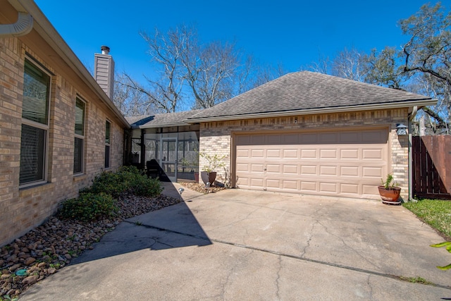 view of property exterior featuring fence, driveway, an attached garage, a shingled roof, and brick siding