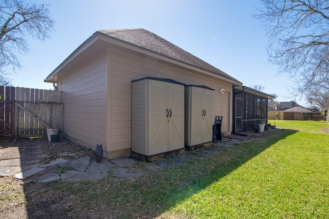 view of shed with fence and a sunroom