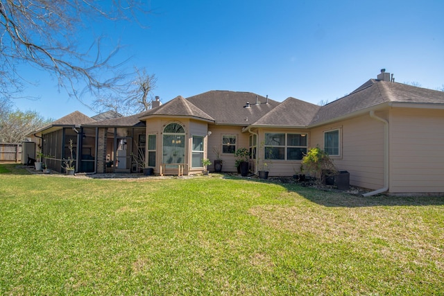 rear view of property featuring a yard, a chimney, and a sunroom